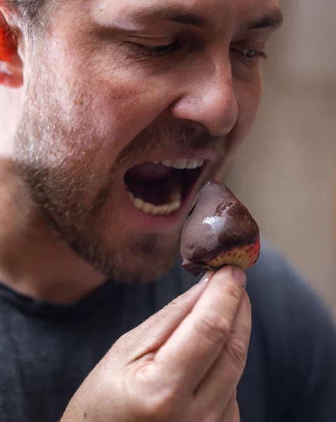 Man eating a chocolate covered strawberry close up portrait