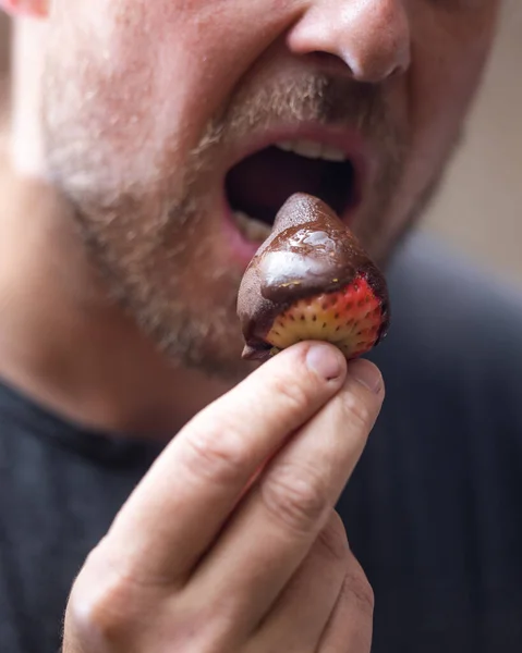 Man eating a chocolate covered strawberry close up portrait