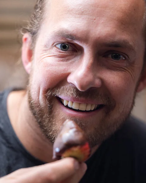 Man eating a chocolate covered strawberry close up portrait