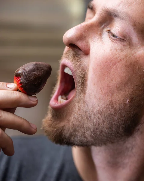 Man eating a chocolate covered strawberry close up portrait