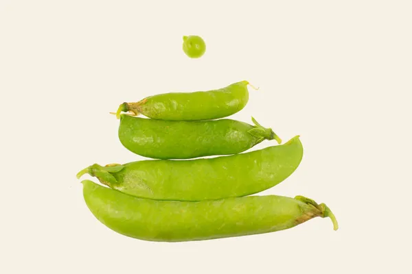 Beyaz arkaplanda taze yeşil bezelyeler.