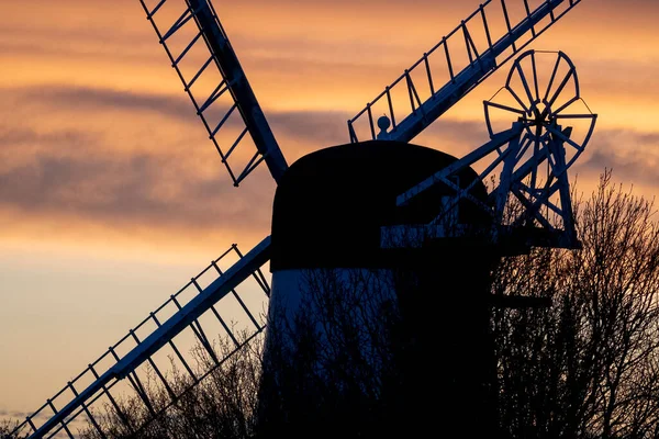 Yel değirmeninin silueti kırsal alanda günbatımında yakalandı