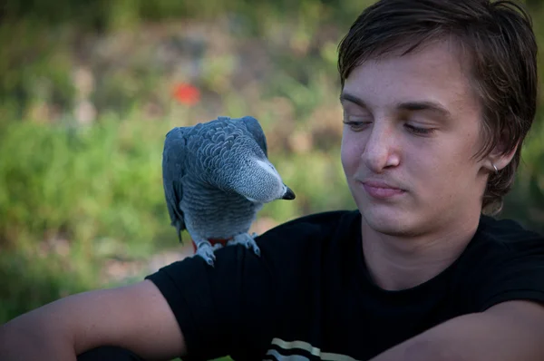 Portret lachende jongen met een papegaai . — Stockfoto