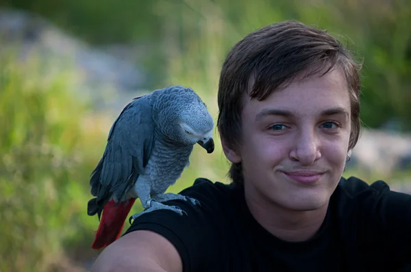 Portret uśmiechnięty chłopiec z papuga . — Zdjęcie stockowe