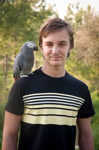 Porträt lächelnder Junge mit einem Papagei . — Stockfoto