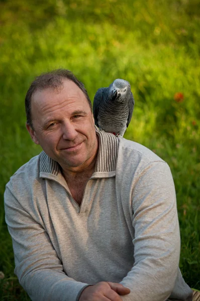 Homem com papagaio sentado no ombro  . Fotos De Bancos De Imagens