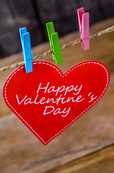 Cute big red heart hanging on the clothesline. On old wood background. — Stock Photo, Image