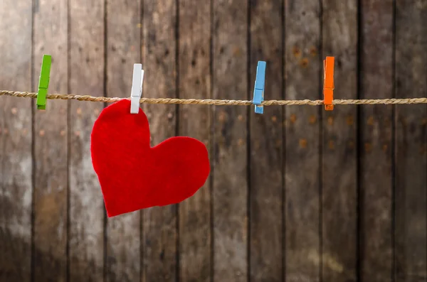 Cute big red heart hanging on the clothesline. On old wood background. — Stock Photo, Image
