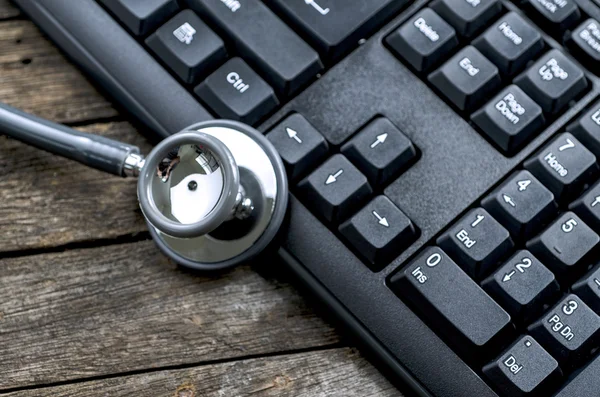 Estetoscopio en un teclado de computadora en madera — Foto de Stock