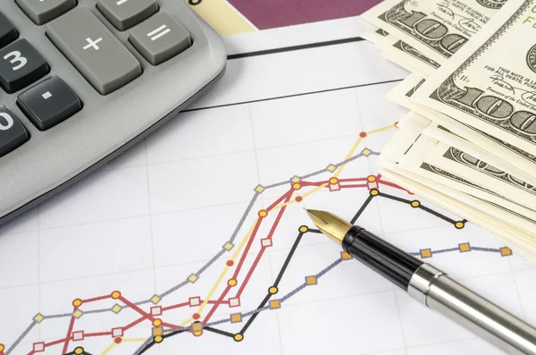 Caneta-tinteiro e calculadora no gráfico financeiro — Fotografia de Stock