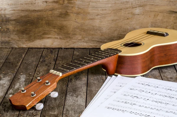 Ukulele und Papier-Akkordschart-Dokument auf Holzgrund — Stockfoto