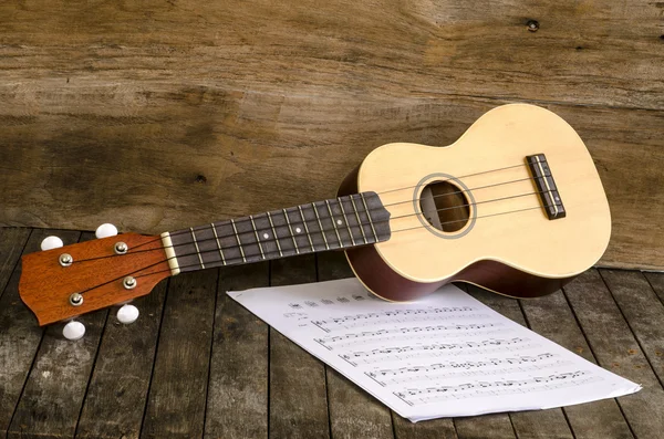 Ukulele en papier chordschart document op houten achtergrond — Stockfoto