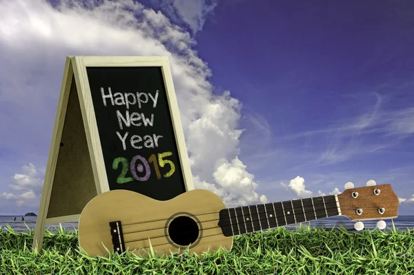 Ukulele med blå himmel och blackboard 2015 text på gräset — Stockfoto