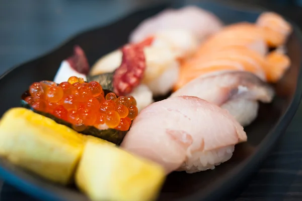Крупный план Икура Сухи в палочках для еды и суши "Variety Set on Black Dish" — стоковое фото