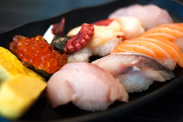Крупный план Икура Сухи в палочках для еды и суши "Variety Set on Black Dish" — стоковое фото
