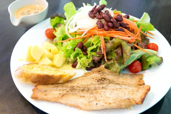 Рибний стейк з салатом, соусом і часниковим хлібом — стокове фото