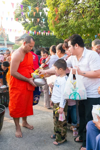 Nonthaburi, thailand - 1 jan 2014 niet-geïdentificeerde boeddhistische monniken worden gegeven voedsel aanbieden van mensen in de ochtend voor Nieuwjaar dag op 31 januari 2014 in sak yai tempel, nonthaburi, thailand Stockfoto