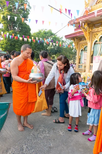Nonthaburi, TAILANDIA - 1 de enero de 2014 Los monjes budistas no identificados reciben ofrendas de comida de la gente por la mañana para el Día de Año Nuevo el 31 de enero de 2014 en el Templo de Sak Yai, en Nonthaburi Tailandia Imágenes de stock libres de derechos