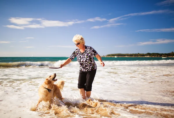Женщина играет на пляже с золотистым ретривером — стоковое фото