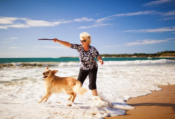 Женщина играет на пляже с золотистым ретривером — стоковое фото