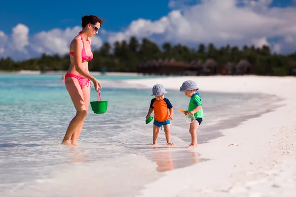 Mãe e gêmeos meninos brincando na praia — Fotografia de Stock