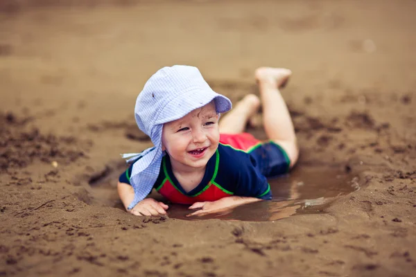 Lilla leende pojke i lera pöl — Stockfoto