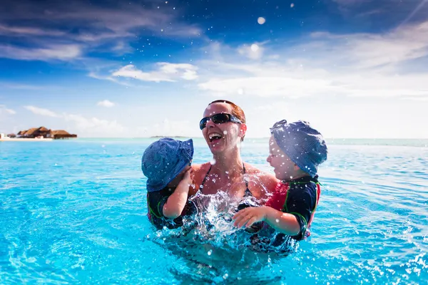 Feliz família salpicando na piscina em um resort tropical Imagens De Bancos De Imagens Sem Royalties