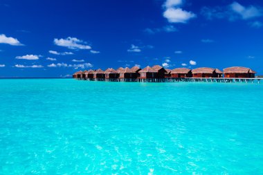 Overwater villas in blue tropical lagoon clipart