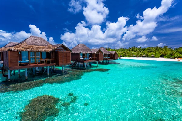 Over water bungalows met stappen in groene koraal lagune — Stockfoto