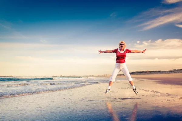 Donna anziana godendo vacanza al mare saltando in aria — Foto Stock