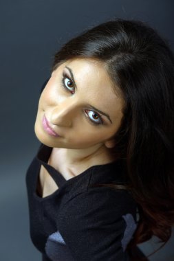 Stüdyoda gri arka planda poz veren genç bir kadın