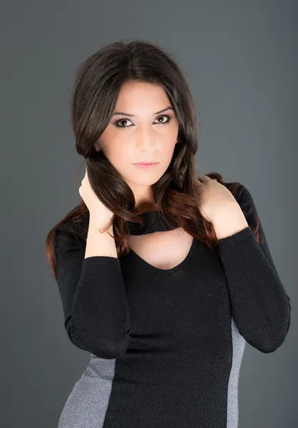 Young woman posing on gray background in studio — Stock Photo, Image