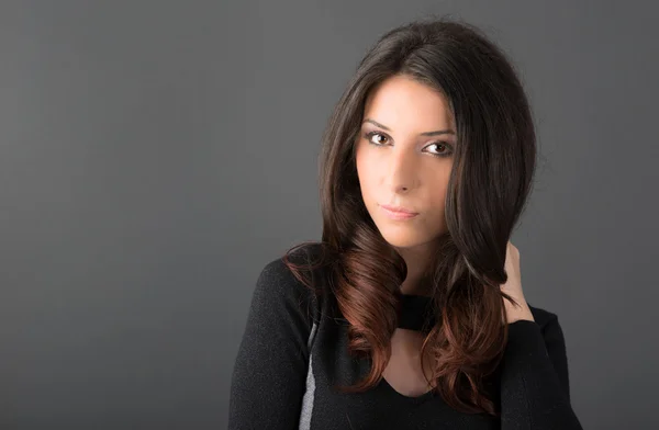 Young woman posing on gray background in studio — Stock Photo, Image