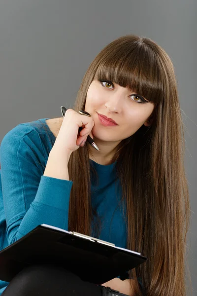 Schöne Frau sitzt auf einem Stuhl und notiert etwas — Stockfoto