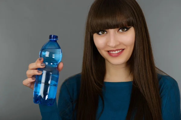 Hermosa mujer con botella de agua aislada en gris — Foto de Stock