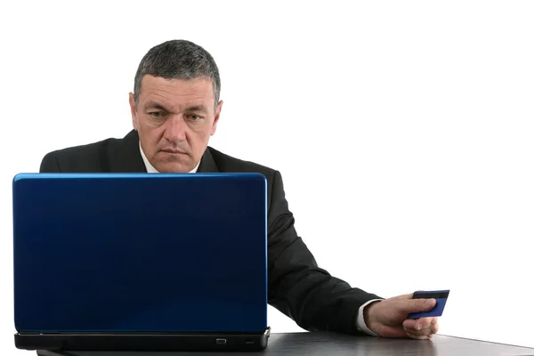 Aged businessman sitting at desk with a laptop isolated on white — Stock Photo, Image