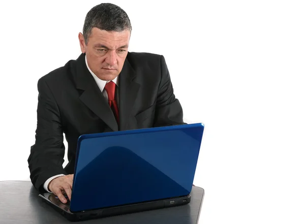 Alter Geschäftsmann sitzt am Schreibtisch mit einem Laptop isoliert auf weiß — Stockfoto