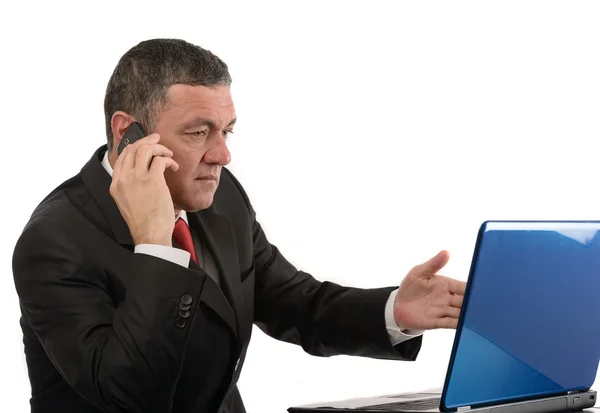 Aged businessman sitting at desk with a laptop isolated on white — Stock Photo, Image