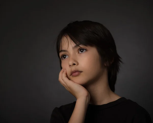 Cute young asian boy looking up with serious look on black backg — Stock Photo, Image