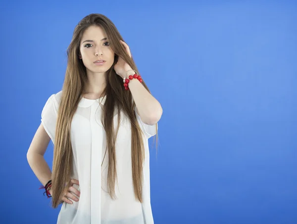 Mladá žena s dlouhými vlasy na modrém pozadí — Stock fotografie