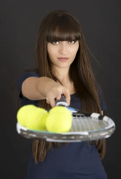 Теннисистка с ракеткой и мячом на черном фоне — стоковое фото