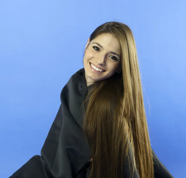 Portret van een jonge vrouw permanent tegen een blauwe achtergrond — Stockfoto