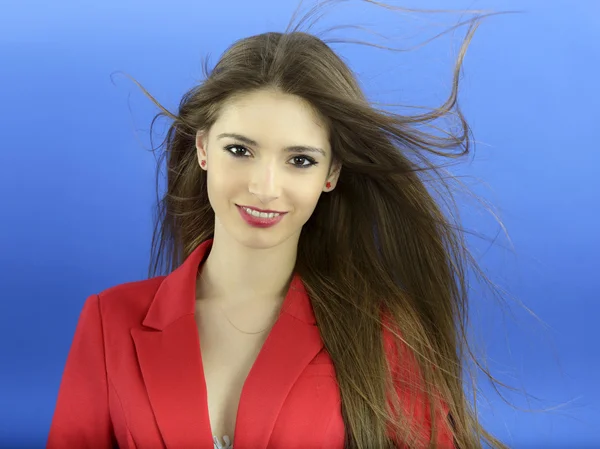 Portrait of a young woman standing against a blue background — Stock Photo, Image