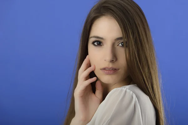 Portret van een jonge vrouw permanent tegen een blauwe achtergrond — Stockfoto