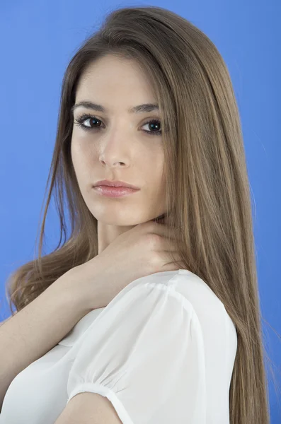 Portrait d'une jeune femme debout sur un fond bleu — Photo