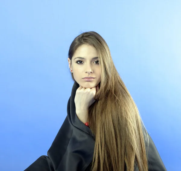 Portret van een jonge vrouw permanent tegen een blauwe achtergrond — Stockfoto