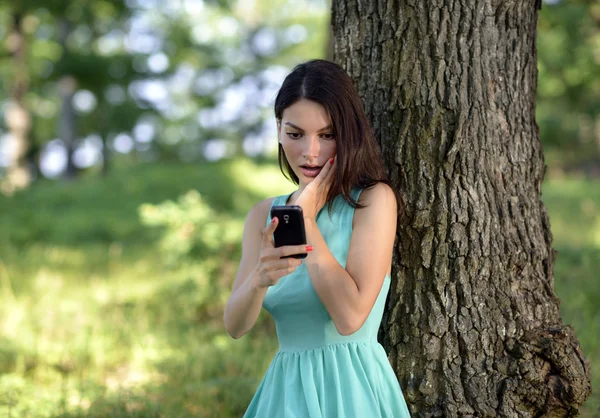 Young woman talking on mobile phone in park — Stock Photo, Image