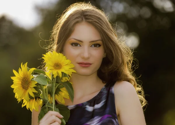 Молодая красивая женщина на цветущем подсолнечнике летом — стоковое фото