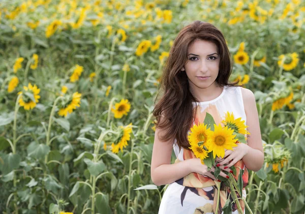 Mladá krásná žena na kvetoucí slunečnice pole v létě — Stock fotografie