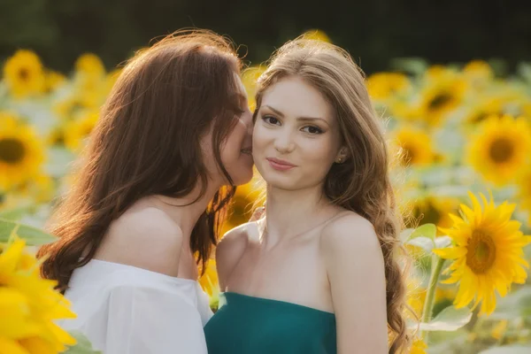 Duas meninas bonitas jovens no campo com flores silvestres, para fora — Fotografia de Stock